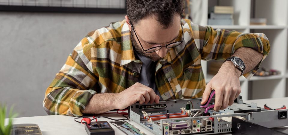 repairman using tongs while fixing broken pc